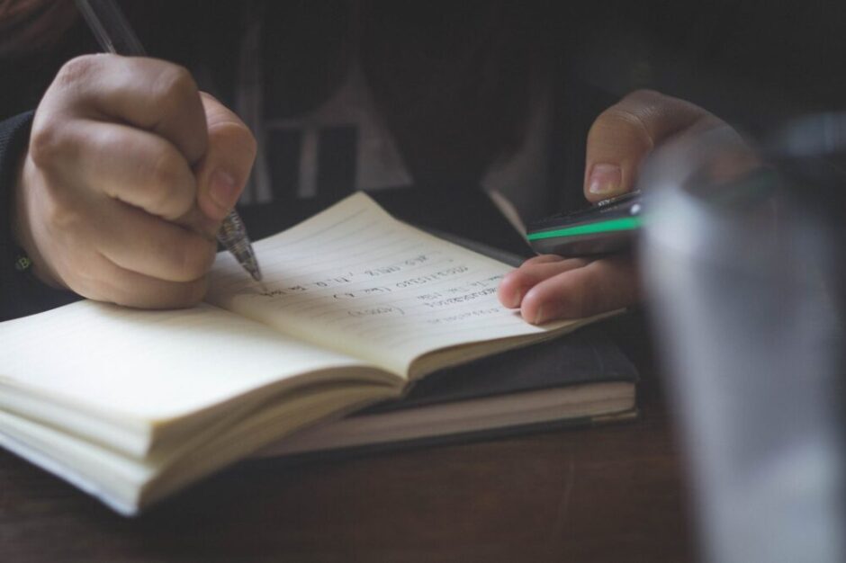 person writing while using phone